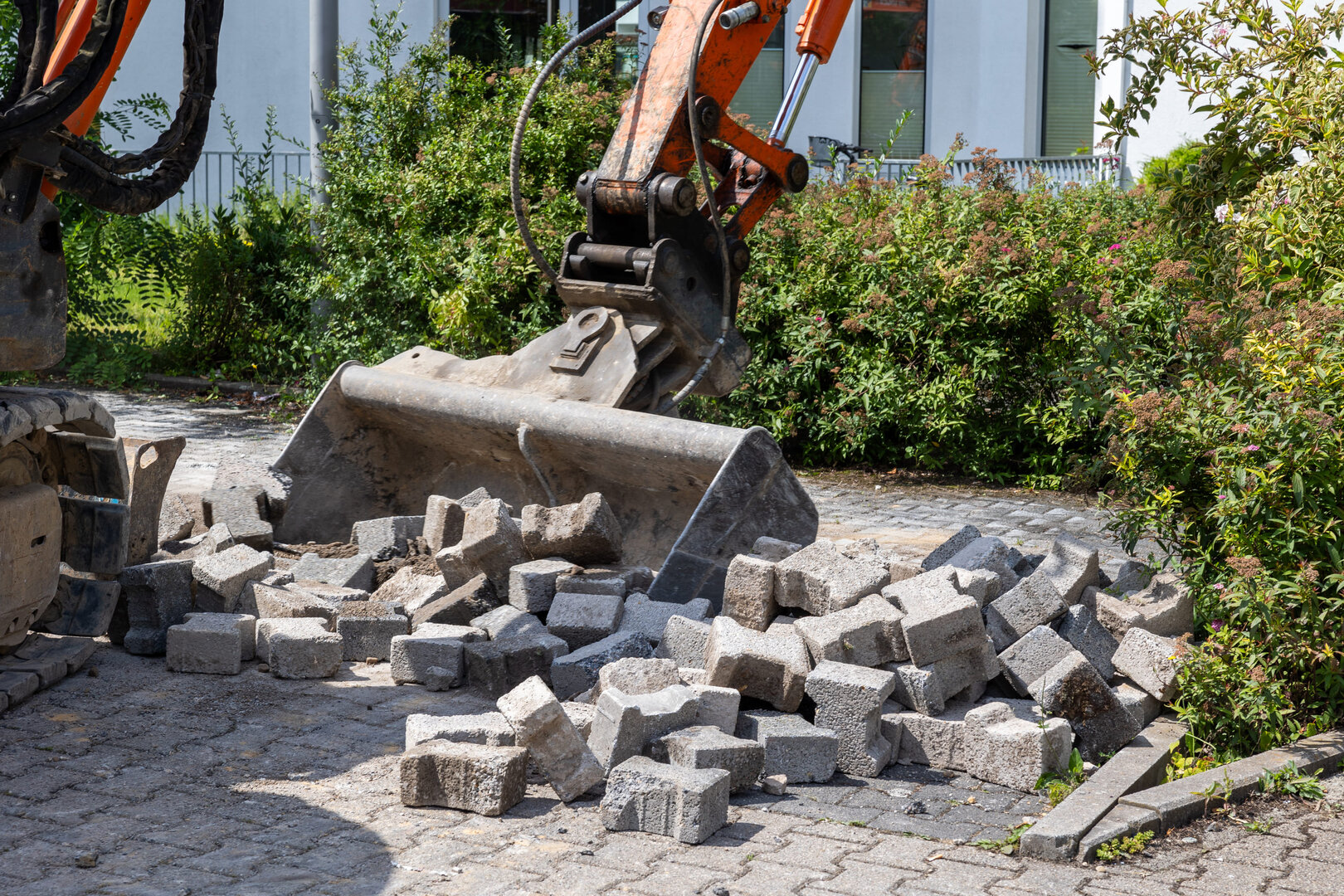 Ein Bagger räumt Steine von den zu sanierenden Parkplätzen weg